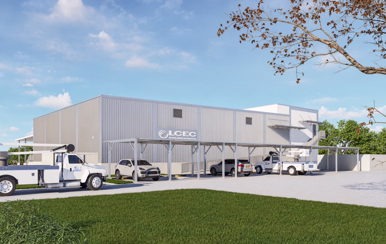 Architectural rendering of the future LCEC West Cape Coral Service Center, featuring a modern white metal building with covered parking, LCEC utility trucks, employee vehicles, and a landscaped exterior under a bright blue sky.